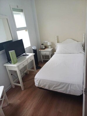 A bedroom with a bed, a desk with a computer, a nightstand with a lamp, and a window. - Hostal Boutique La Malagueña Only Adults by Croma (Estepona)