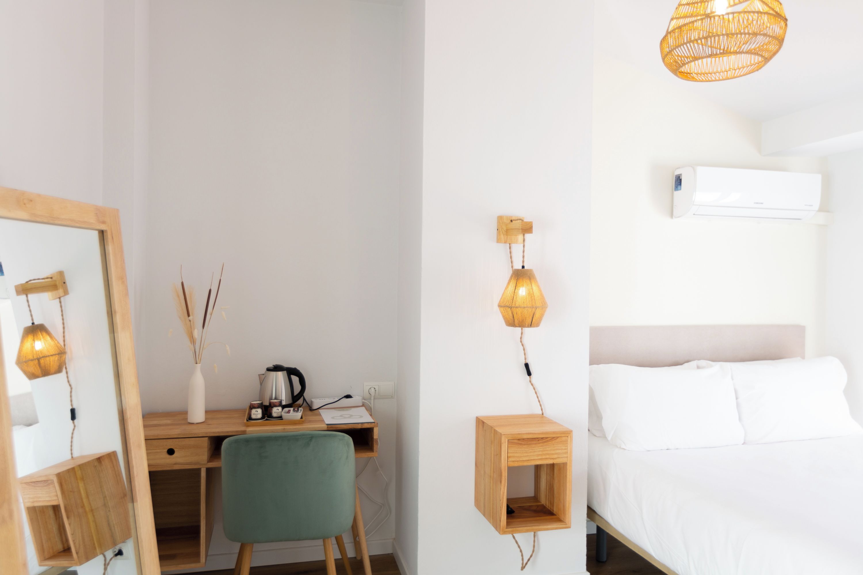 Un dormitorio con una cama, un escritorio con silla, un espejo y una lámpara colgante.