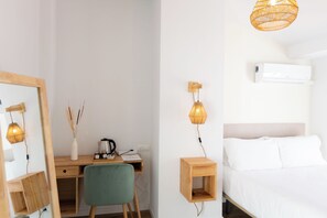 A bedroom with a bed, a desk with a chair, a mirror, and a hanging light fixture. - Hostal Boutique La Malagueña Only Adults by Croma (Estepona)