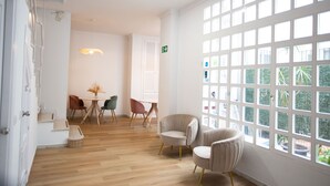 A bright room with a large window, a wooden floor, and a table with chairs. - Hostal Boutique La Malagueña Only Adults by Croma (Estepona)