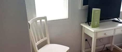 A small room with a white desk, a chair, and a computer monitor.