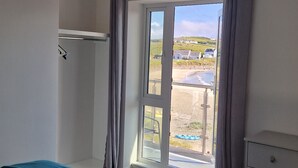Une chambre à coucher avec un lit, une commode, une fenêtre avec des rideaux et une vue sur un paysage.