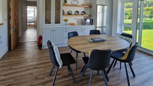 Une cuisine moderne avec des meubles blancs, un four à micro-ondes et un coin repas comprenant une table ronde en bois et des chaises.