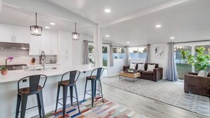 A modern kitchen with white cabinets, a central island with bar stools, and pendant lighting. - Family-Friendly Modern Escape in San Diego (San Diego)