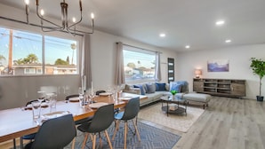 A modern living room with a dining area, large windows, a chandelier, and a view of the outside. - Family-Friendly Modern Escape in San Diego (San Diego)