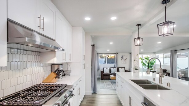 A modern kitchen with white cabinets, a stainless steel stove, and a large island with a sink. - Family-Friendly Modern Escape in San Diego (San Diego)