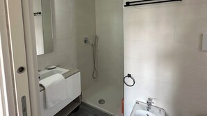 A modern bathroom with a glass-enclosed shower, a white sink, and a bidet. - Guest house with direct access to the beach (Portici)