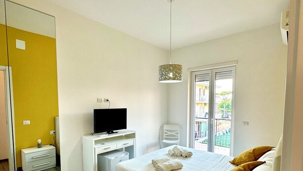 A modern bedroom with a bed, a desk, a television, and a window. - Guest house with direct access to the beach (Portici)