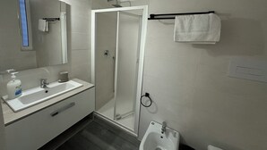 A modern bathroom with a glass-enclosed shower, a sink with a mirror, and a bidet. - Guest house with direct access to the beach (Portici)