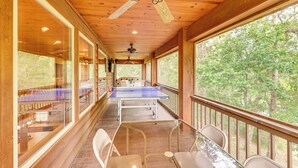 A wooden deck with a ping pong table, chairs, and a ceiling fan. - Riverfront Cabin on 2 Acres in Glenwood! (Glenwood)