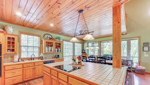 A spacious kitchen with wooden cabinets, a large island, and a hanging light fixture. - Riverfront Cabin on 2 Acres in Glenwood! (Glenwood)
