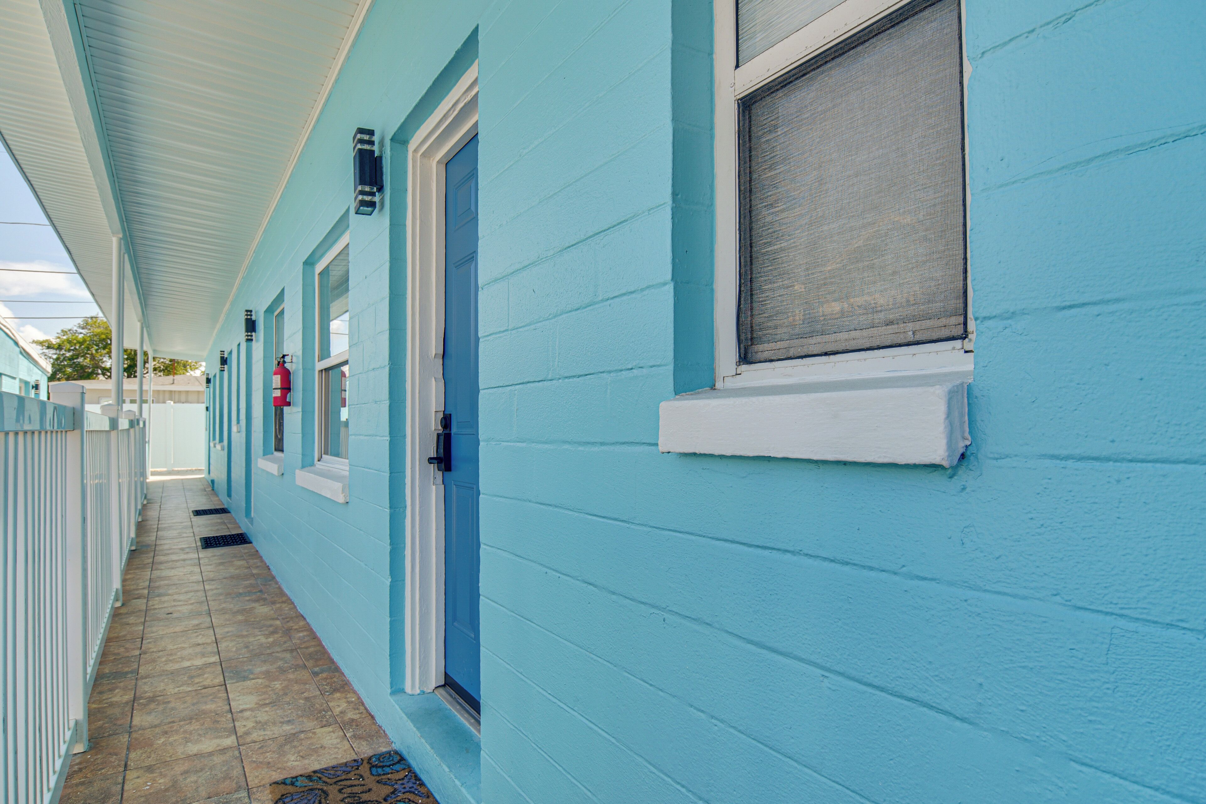 A corridor with a blue exterior, a door, and a window with a screen.