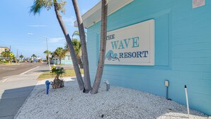En bygning med et skilt der viser 'The Wave Resort' og palmer foran.