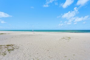 Ein weiter Sandstrand mit blauem Himmel und Meer.