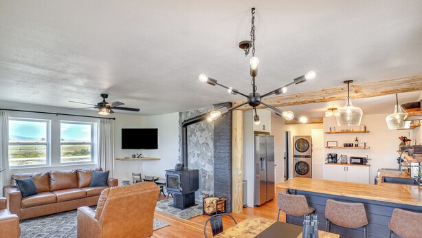 A modern living room with a sofa, a dining table, and a kitchen area with a stove and refrigerator.