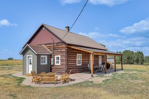 A log cabin with a covered porch and outdoor seating area. - Mountain-View Log Cabin in Wyoming Wilderness (Encampment)