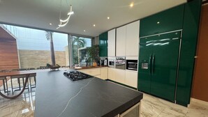 A modern kitchen with a marble countertop, green cabinets, and a built-in refrigerator. - Casa Lujosa, piscina, sala de cine y chimenea. Barrio mas cool del mundo (Medellín)