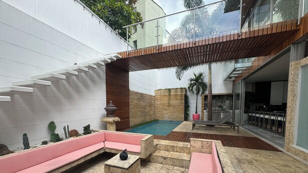 A modern outdoor patio with a pool, seating areas, and a wooden pergola. - Casa Lujosa, piscina, sala de cine y chimenea. Barrio mas cool del mundo (Medellín)