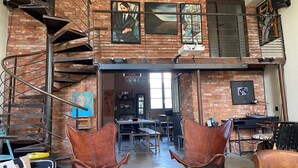 A loft-style interior with exposed brick walls, a spiral staircase, and various artworks. - Grand Loft Dartiste en Avec Équipement Professionnel Audio et Vidéo (Angoulême)