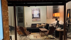A spacious living area with a brick wall, a sofa, a coffee table, and a dining table. - Grand Loft Dartiste en Avec Équipement Professionnel Audio et Vidéo (Angoulême)