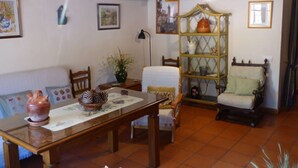 Un salon chaleureux avec une table en bois, des chaises, un canapé, une bibliothèque et une lampe.