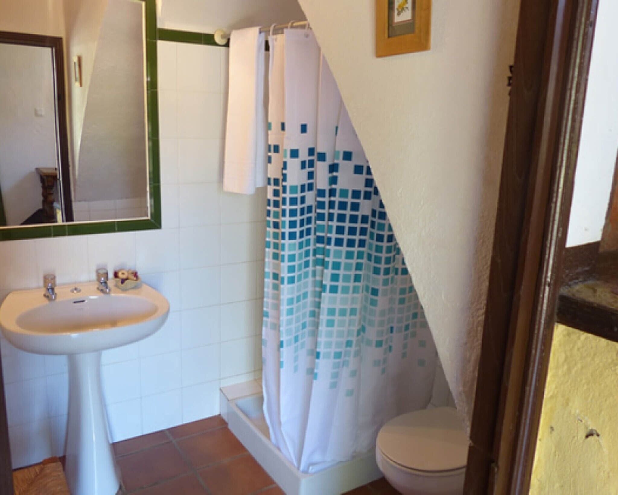Un baño con lavamanos, inodoro y cortina de ducha.