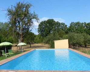 A rectangular swimming pool with a tiled edge, surrounded by a grassy area and trees. - Country House 'Los Cascos' with Mountain View, Shared Pool and Air Conditioning (Huelva)