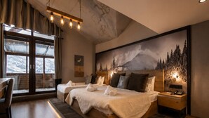 A modern bedroom with a large bed, a desk, and a view of mountains through large windows. - Magna Chalet Otel (Kayseri)