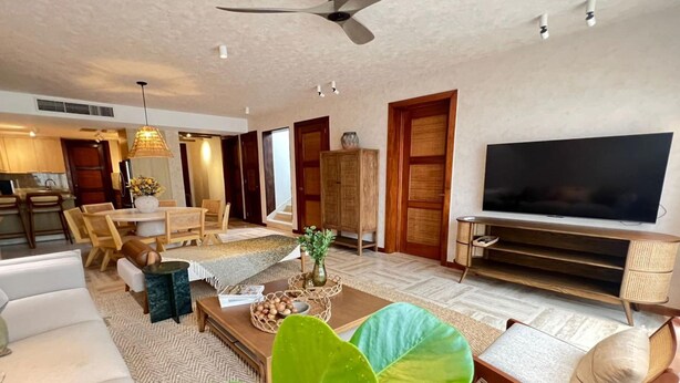 Een moderne woonkamer met een bank, salontafel, televisie en een eetgedeelte met stoelen en een tafel.