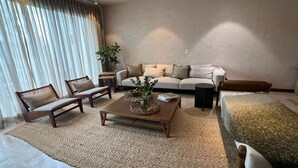 Een moderne woonkamer met een bank, twee fauteuils, een salontafel en een bijzettafeltje.