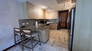 Een moderne keuken met houten kastjes, een granieten aanrecht en een roestvrijstalen koelkast.