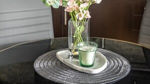 Een moderne keuken met donkere kastjes, een marmeren aanrecht en een vaas met bloemen op een glazen tafel.