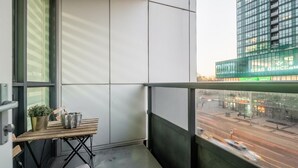A balcony with a view of a busy street and a building with a green facade.