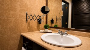 A bathroom with a large mirror, a sink, and a towel rack.