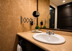 A bathroom with a large mirror, a sink, and a towel rack.