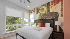 Un dormitorio moderno con una cama grande, cabecera de madera y vistas al exterior.