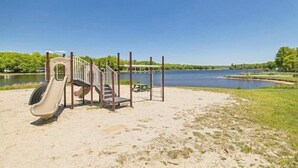 Un parque infantil con tobogán y estructura para escalar cerca de un lago.