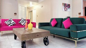 A living room with a pink sofa, a green sofa, a wooden coffee table, and a colorful vase. - Bright, pet-friendly home near Summerlin and The Lakes (Las Vegas)