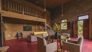 Un vaste salon doté d’un haut plafond, d’un escalier, d’un téléviseur à écran plat et d’un coin repas avec une table ronde et des chaises.
