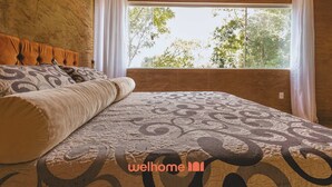 Une chambre à coucher avec un grand lit, une tête de lit en bois et une fenêtre avec des rideaux.