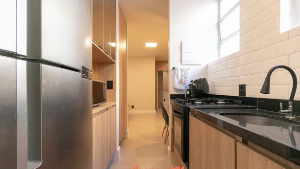 Una cocina moderna con electrodomésticos de acero inoxidable, encimera negra y armarios de madera.