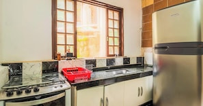 A kitchen with a gas stove, a sink, a refrigerator, and a window with a view. - Casa em Angra dos Reis perto da Praia Jardim (Angra dos Reis)