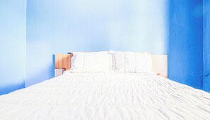A bed with white bedding in a room with blue walls. - Casa em Angra dos Reis perto da Praia Jardim (Angra dos Reis)