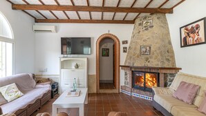 A cozy living room with a stone fireplace, a television, and comfortable seating.
