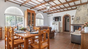 A spacious living area with a wooden dining table, comfortable seating, a fireplace, and a stone wall.