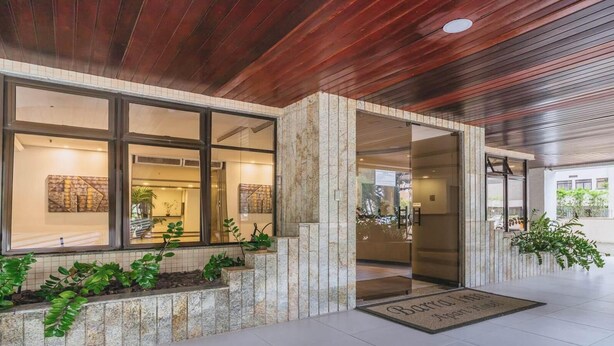 L’entrée d’un hôtel moderne, avec une façade en pierre, de grandes fenêtres et un plafond en bois.