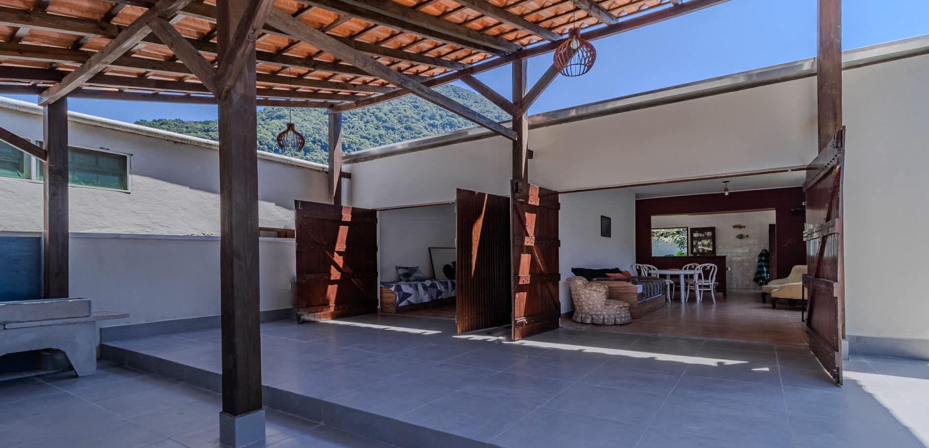A covered outdoor area with a patio, a dining area, and a view of a mountainous landscape.