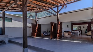 Un espacio al aire libre techado con un patio, comedor y vistas a un paisaje montañoso.