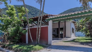 Un edificio de dos pisos con fachada roja y blanca, un porche cubierto y vistas a un paisaje montañoso.