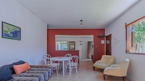 Una sala de estar con un sofá, una mesa de comedor con sillas, una pared de acento roja y vistas al exterior.